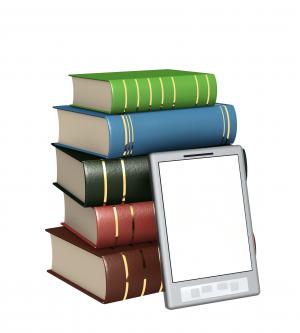 A pile of books with an e-reader leaning against them